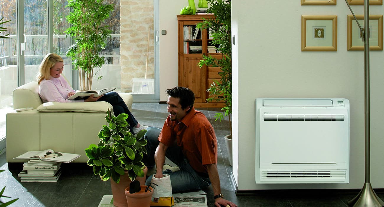 Woman and man sitting in living room next to ductless mini split system.