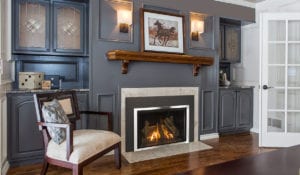 A lit gas fireplace in a traditional living room with gray walls and gray cabinets on each side.