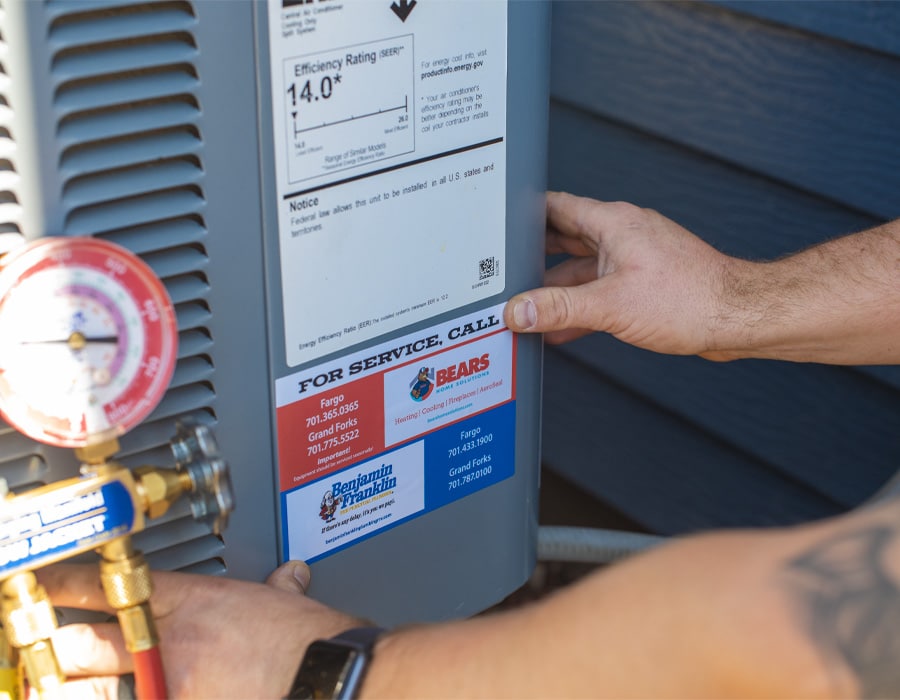 A closeup of a technician’s hands placing a service sticker on an outdoor air conditioner