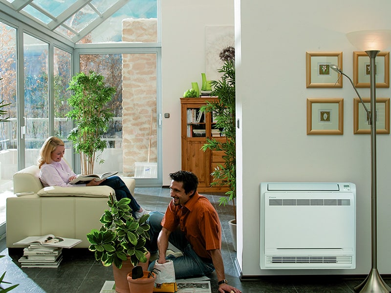 A man and a woman relaxing near a mini split air conditioner in their living room