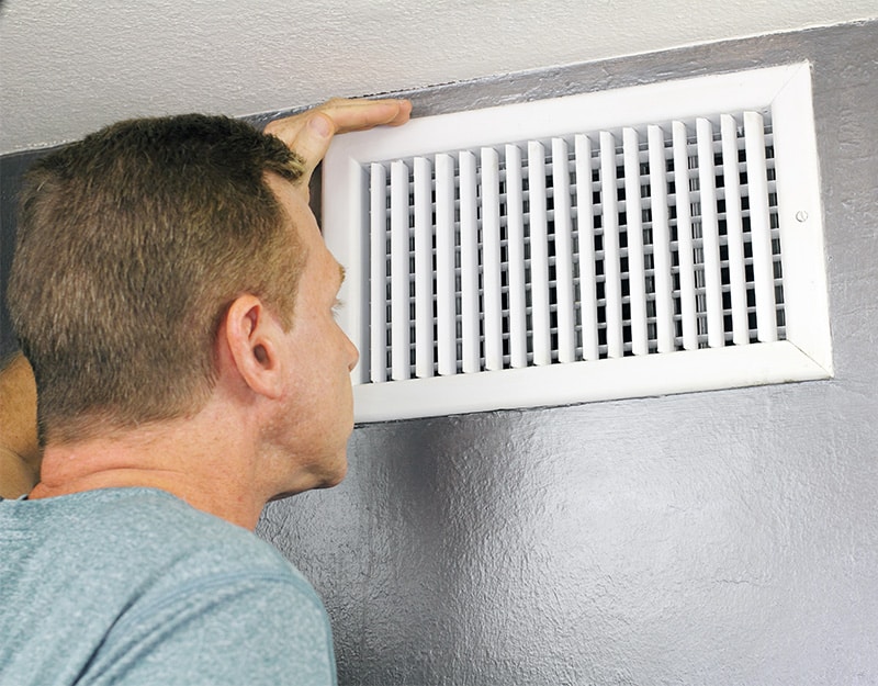 Man looks into open house vent.