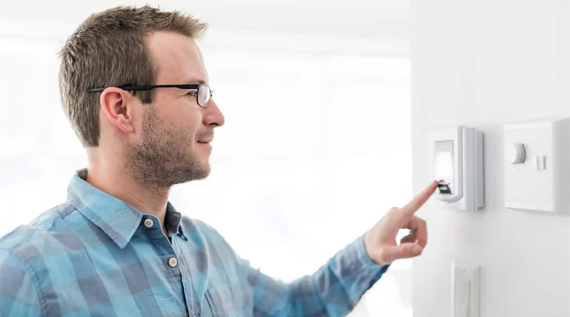 Man presses button on in-home thermostat.