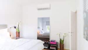 A brightly lit bedroom with a mini split air handling unit on the wall