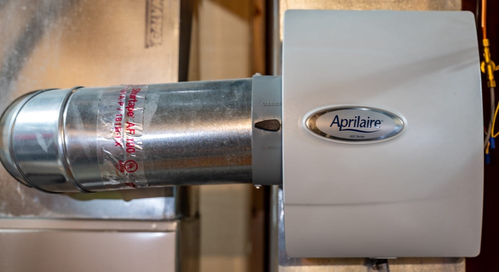 A whole-home Aprilaire humidifier in the mechanical room of a house.
