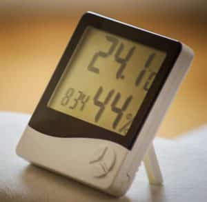 A white hygrometer showing measurements of humidity in a home