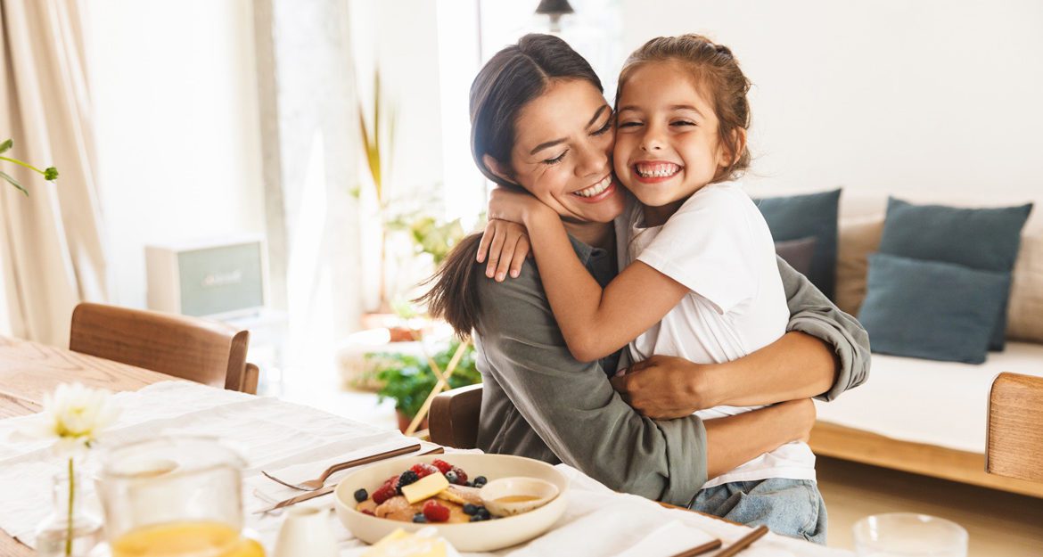 A mother and daughter hugging at breakfast