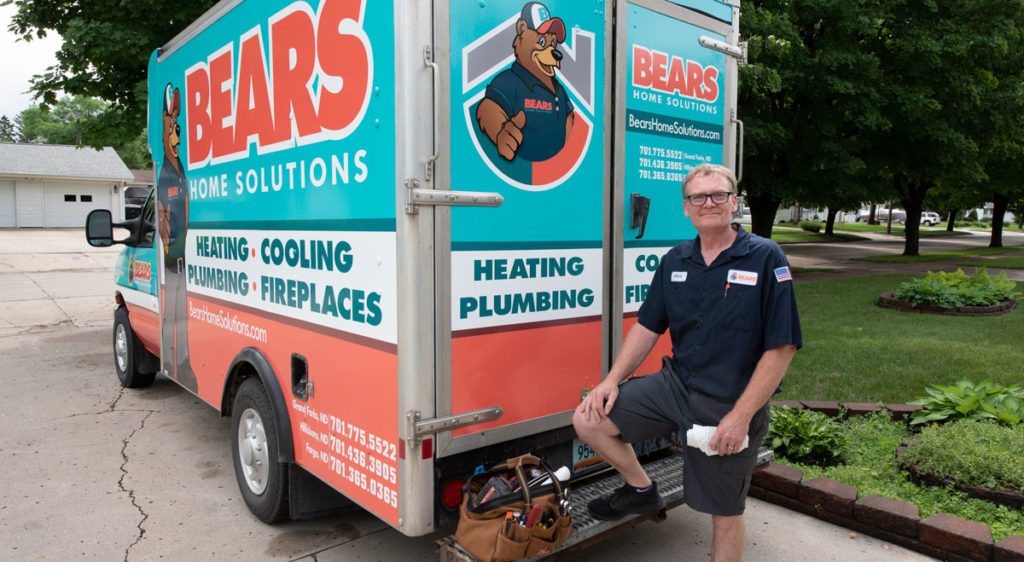 A male Bears Home Solutions HVAC service technician smiling as he poses for a photo by his service van.