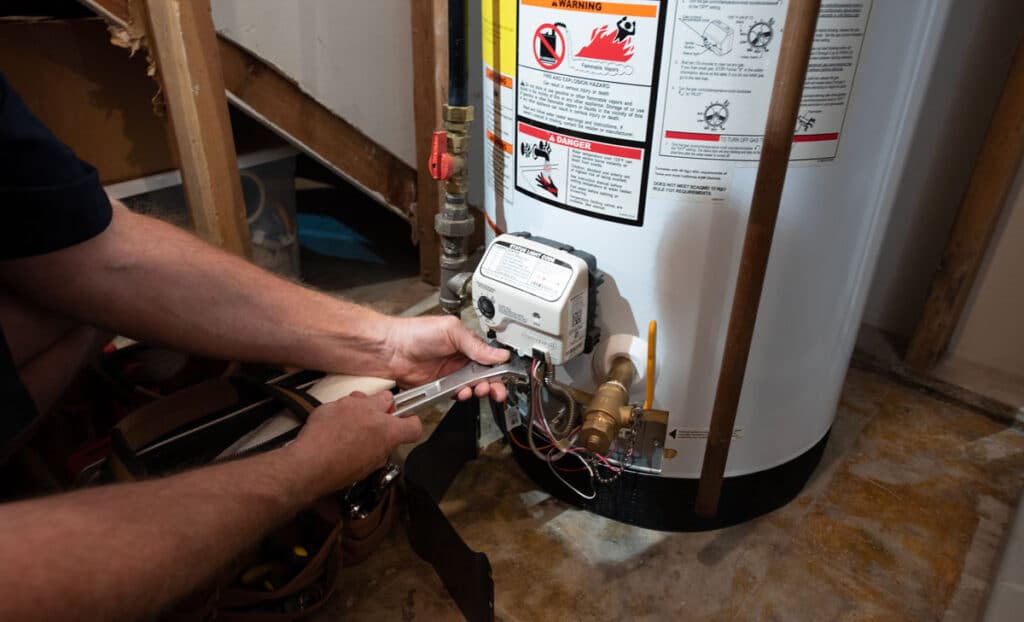 A Bears Home Solutions plumber fixing a water heater with a wrench in a home