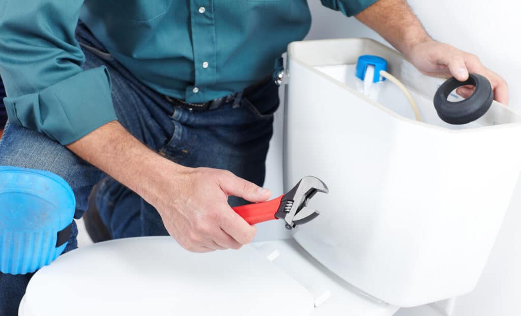 Person making repairs to a toilet