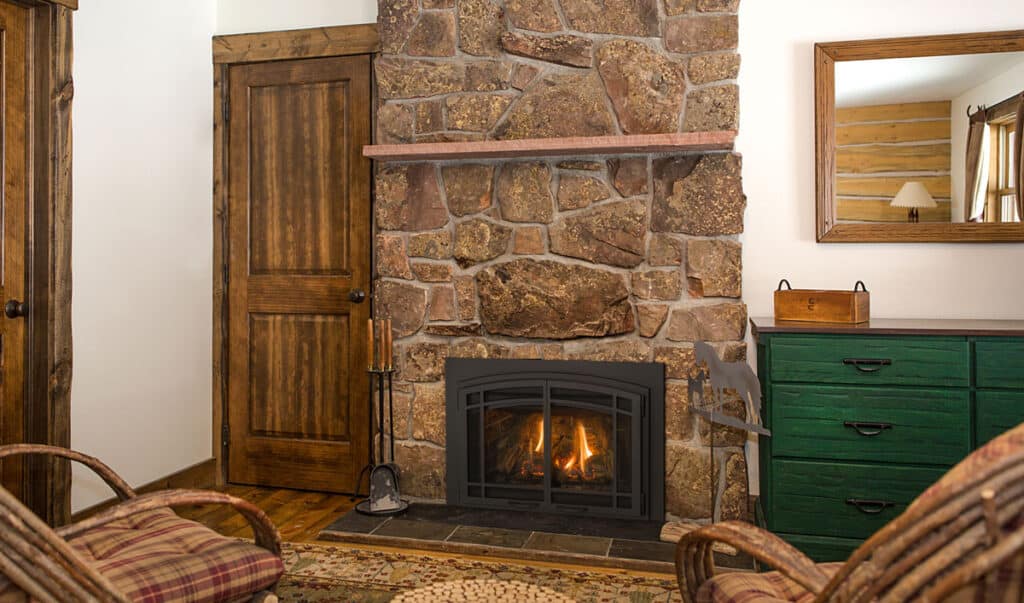 A Chaska Kozy Heat fireplace insert surrounded by stone