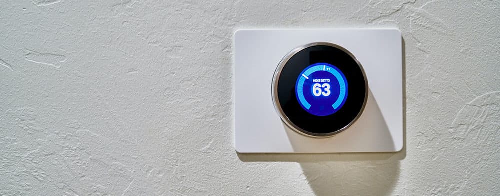 A digital thermostat on a white wall 