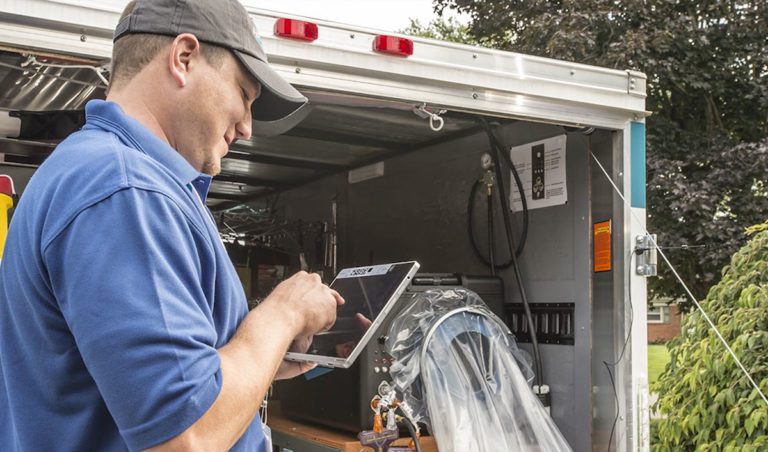 A male Aeroseal technician standing next to his equipment as he checks for air leakage in the ductwork of a home