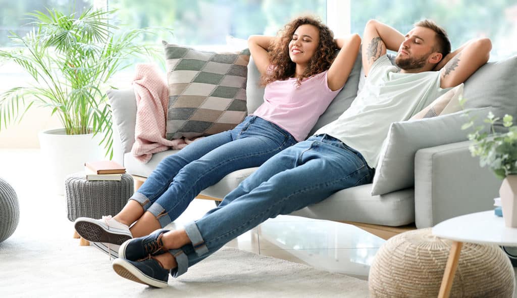 A young man and woman relaxing on a couch in a living room