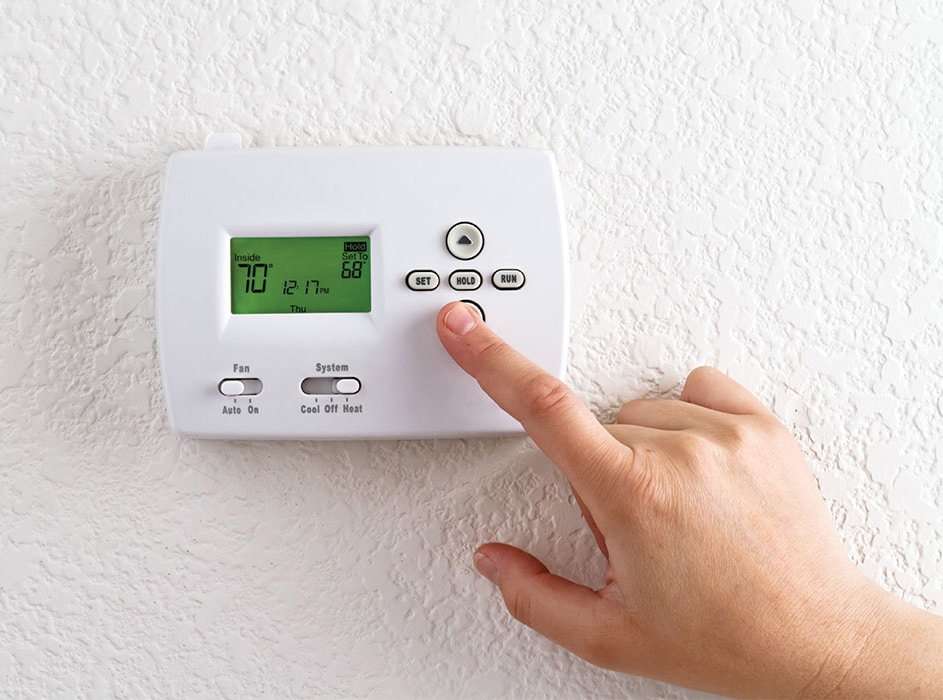 Person adjusting a thermostat
