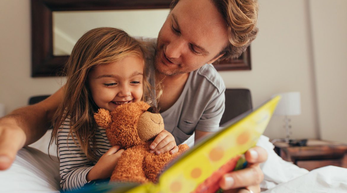 A father reading a bedtime story to his young daughter