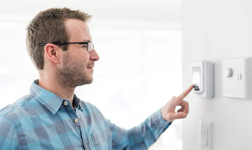 Man presses button on in-home thermostat.