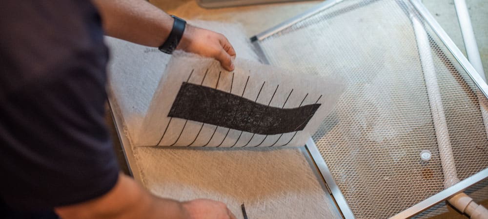 A closeup of a male heating and cooling technician changing the air filter in a home furnace